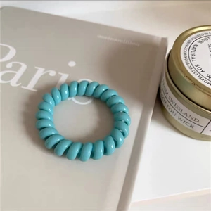 Nahaufnahme eines himmelblauen Spiral-Haargummis auf einem minimalistischen Schreibtisch