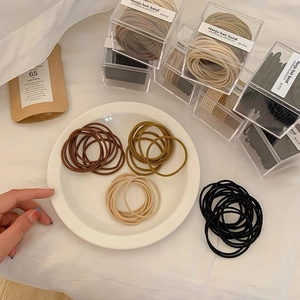 Détails d'élastiques à cheveux de tons terreux dans une boîte en plastique claire
