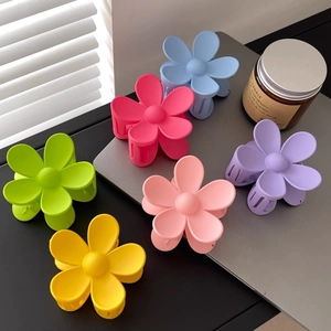 Lot de pinces à cheveux fleur mates en six couleurs vives sur un bureau moderne épuré