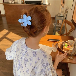Gros plan d'une pince à cheveux fleur bleue mate utilisée pour un chignon français