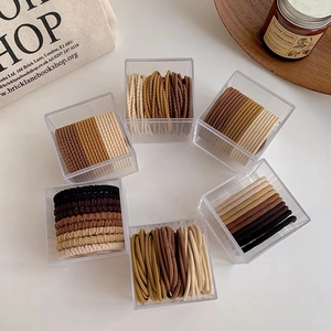 Vue détaillée d'élastiques à cheveux haute élasticité aux tons terre en boîtes acryliques
