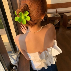 Gros plan d'une pince à cheveux fleur vert fluo à texture mate sur un chignon