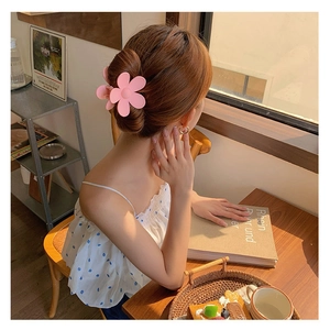 Pince à cheveux fleur rose mat présentée sur un chignon élégant de style coréen