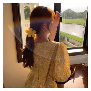 Vue détaillée d'une pince à cheveux fleur jaune sur mannequin sous lumière douce
