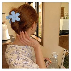 Détail d'une pince à cheveux fleur bleue claire stylisée sur une coiffure tressée