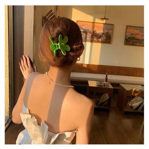 Pince à cheveux fleur vert citron mat, présentée sur un chignon de mannequin