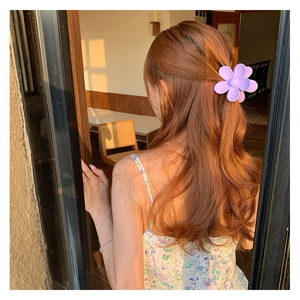 Gros plan d'une pince à cheveux fleur violette mate sur de longs cheveux ondulés