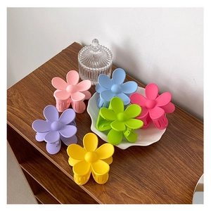 Gros plan de pinces à cheveux fleurs mates en six couleurs sur une assiette décorative