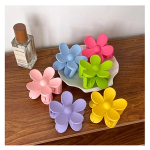 Lot de six pinces à cheveux en forme de fleur aux couleurs macarons sur table en bois