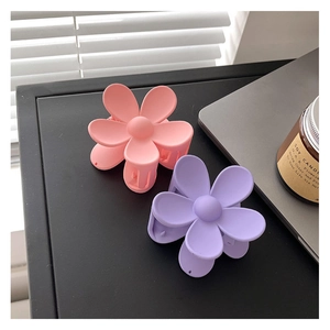 Détail de pinces à cheveux fleurs mates rose et violette dans un décor moderne épuré