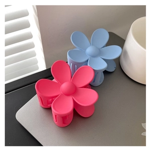 Gros plan de pinces à cheveux fleur en plastique mat rose et bleu sur un bureau