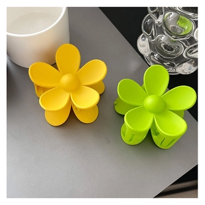 Gros plan de pinces à cheveux fleurs mates en jaune et vert sur une surface grise