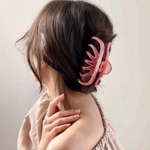 Detail showing a large translucent pink claw clip holding thick hair in a French bun