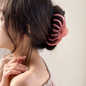 Macro detail of large translucent pink claw clip holding thick hair in a French bun style
