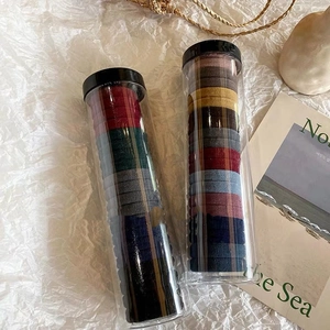 Close-up of colorful elastic hair bands stored in two clear cylindrical jars for easy storage