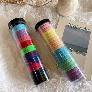 Pastel and dark elastic hair ties set in clear cylindrical jars with black lids