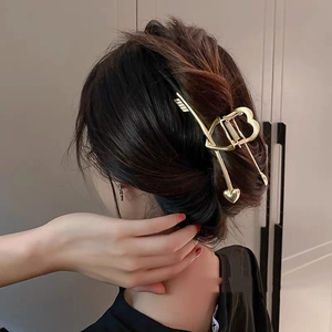 Détail de la pince à cheveux dorée flèche de Cupidon avec motif cœur élégant