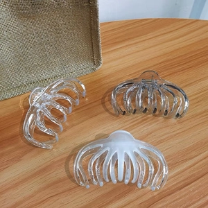 Close-up of three large transparent and cream shark hair claws on a wooden background