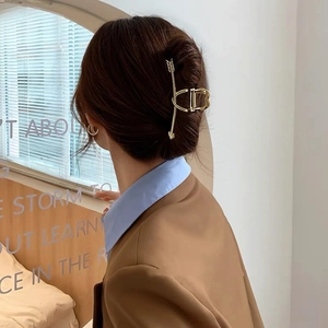 Vue détaillée de la pince à cheveux flèche dorée élégante portée sur un modèle avec style