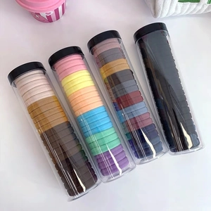 Close-up of four transparent jars filled with high-elastic colorful hair ties on a desk