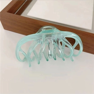 Macro detail of mint green translucent hair claw clip with multi-tooth octopus design