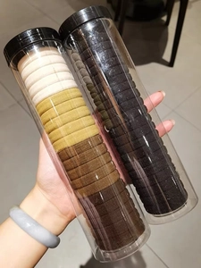 Close-up of dual transparent tubes filled with multi-color high elastic hair ties