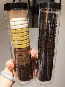 Close-up of high elasticity hair ties in clear jars with neutral and black color options