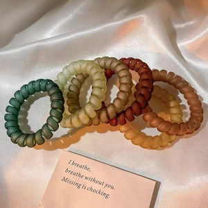 Détail de six élastiques spirales mats aux tons terre sur du satin blanc élégant
