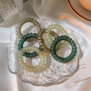 Vue détaillée d'élastiques spirales mats en vert et olive sur un tissu en soie