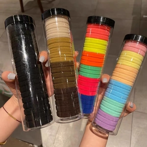 Hand holding four jars of high-elastic seamless hair ties in assorted color palettes