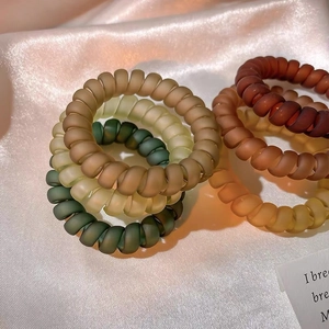 Détail d'élastiques à cheveux spirales mats aux tons terreux sur fond de tissu en soie