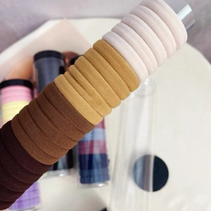Close-up of high-elastic seamless hair ties in earth tones on transparent storage tube