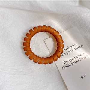 Vue détaillée d'un élastique spirale mat ambre sur un fond en tissu de lin minimaliste