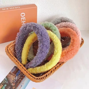 Close-up of colorful plush lamb wool headbands in various candy colors inside a woven basket