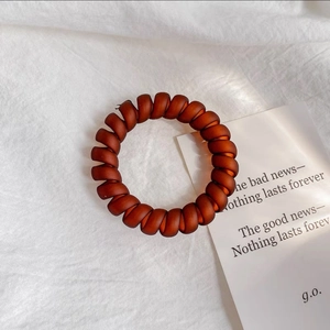 Détail d'un élastique spirale marron rouge foncé givré sur un tissu en lin blanc