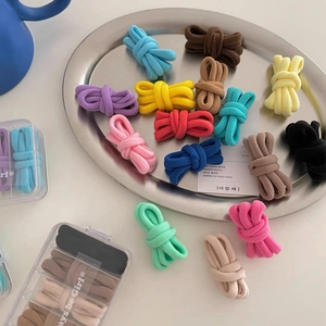 Close-up of seamless colorful elastic hair ties in a clear storage box on a silver tray