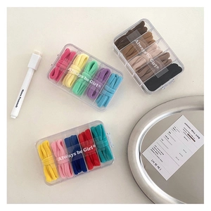 Detailed top view of colorful seamless hair ties in three clear five-slot organizer boxes