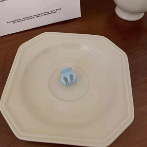 Close-up of a light blue matte hair claw clip on an octagonal ceramic plate
