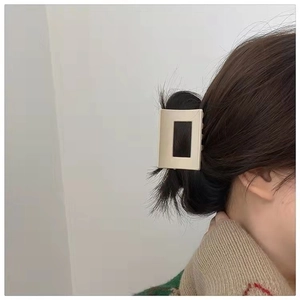 Close-up of a matte beige rectangular hair claw clip worn on hair for a minimalist look