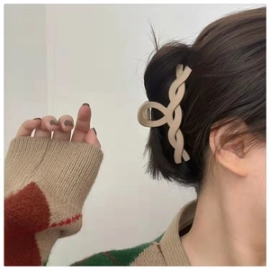 Close-up of a large beige matte hair claw clip in a stylish cross-woven design on model