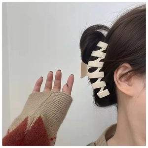 Detail view of large cream-colored wave-shaped matte hair claw clip in a hair bun