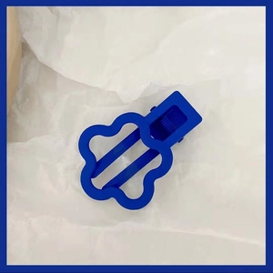 Macro shot of a Klein blue hollow floral hair clip on a textured white background
