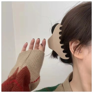 Close-up of a large cream-colored matte hair claw clip styled on a woman's brown wavy hair