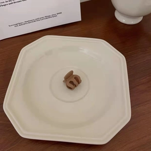 Detailed view of matte coffee mini hair claw clip on an octagonal ceramic tray