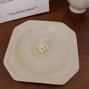 Detailed view of a small cream hair claw clip placed on a white ceramic display tray