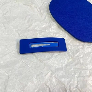 Close-up of matte Klein blue rectangular snap hair clip on white textured paper