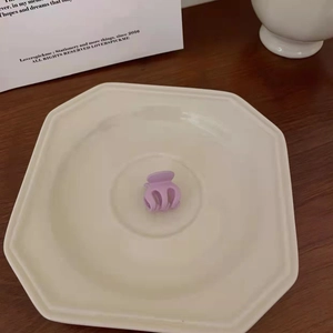 Detailed view of a small matte lavender hair claw clip on a minimalist ceramic plate
