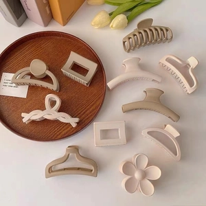 Detailed set of matte hair claws in neutral beige and milk coffee tones on a white desk