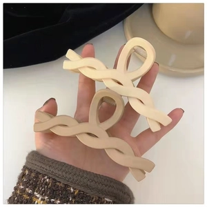 Close-up of cream and beige woven matte hair claws held by hand for thick hair