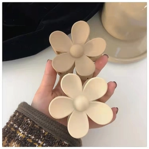 Matte flower hair claws in milk tea and cream white colors held by hand for styling